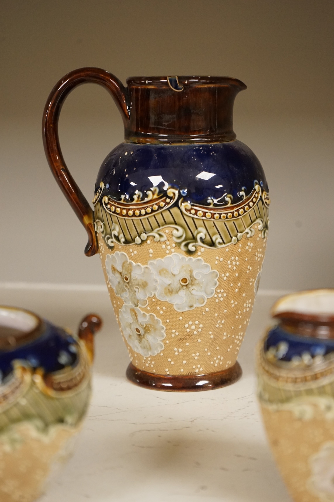A small collection of Doulton Lambeth stoneware comprising, tea and coffee pots, two jugs and sugar bowl, largest 21cm high